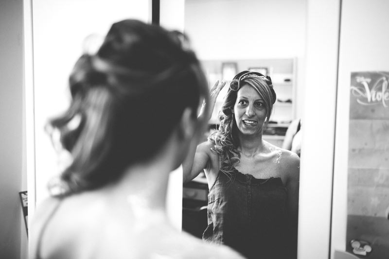 la mariée se regarde dans le miroir sous l'oeil du photographe