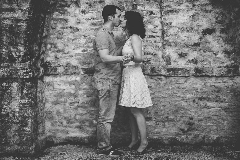 couple kissing in front of stone wall