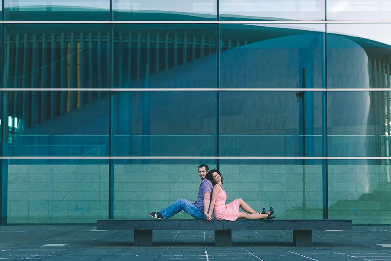 couple sitting on bench in front of the opera of luxembourg