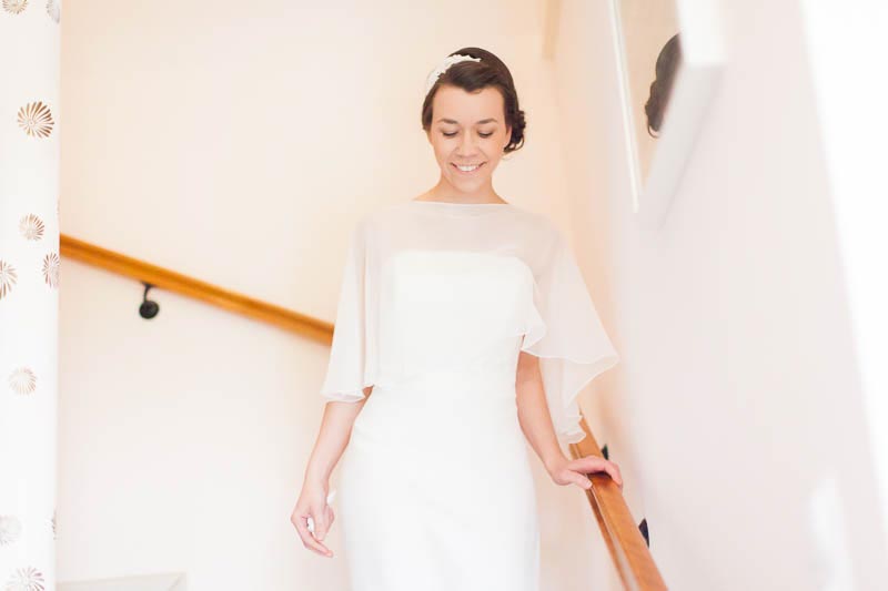the bride walks down the stairs of her homeplace