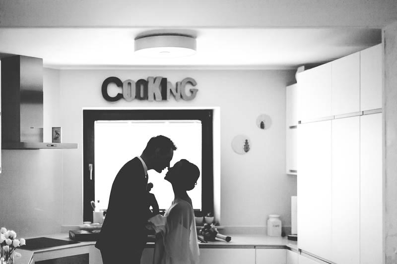 bride and groom kissing in their kitchen