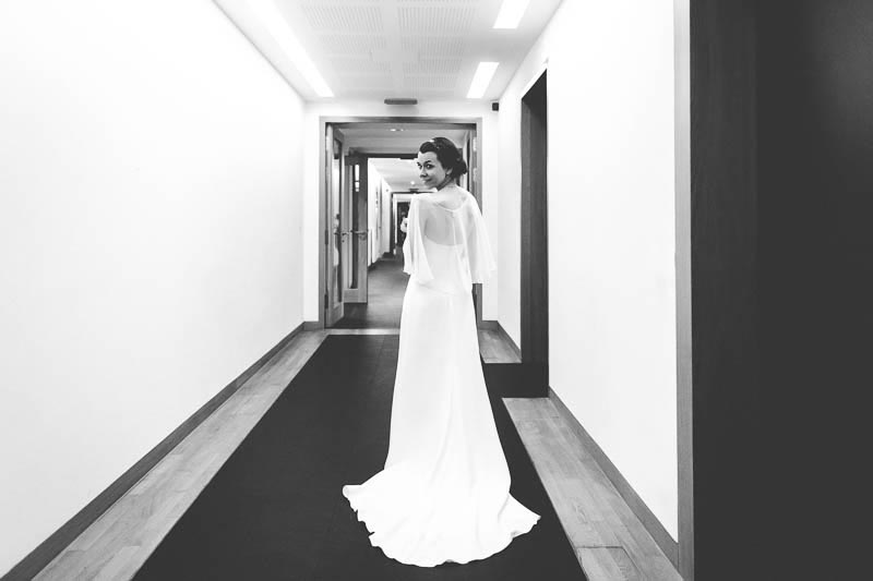 the bride in her dress walking down a long corridor