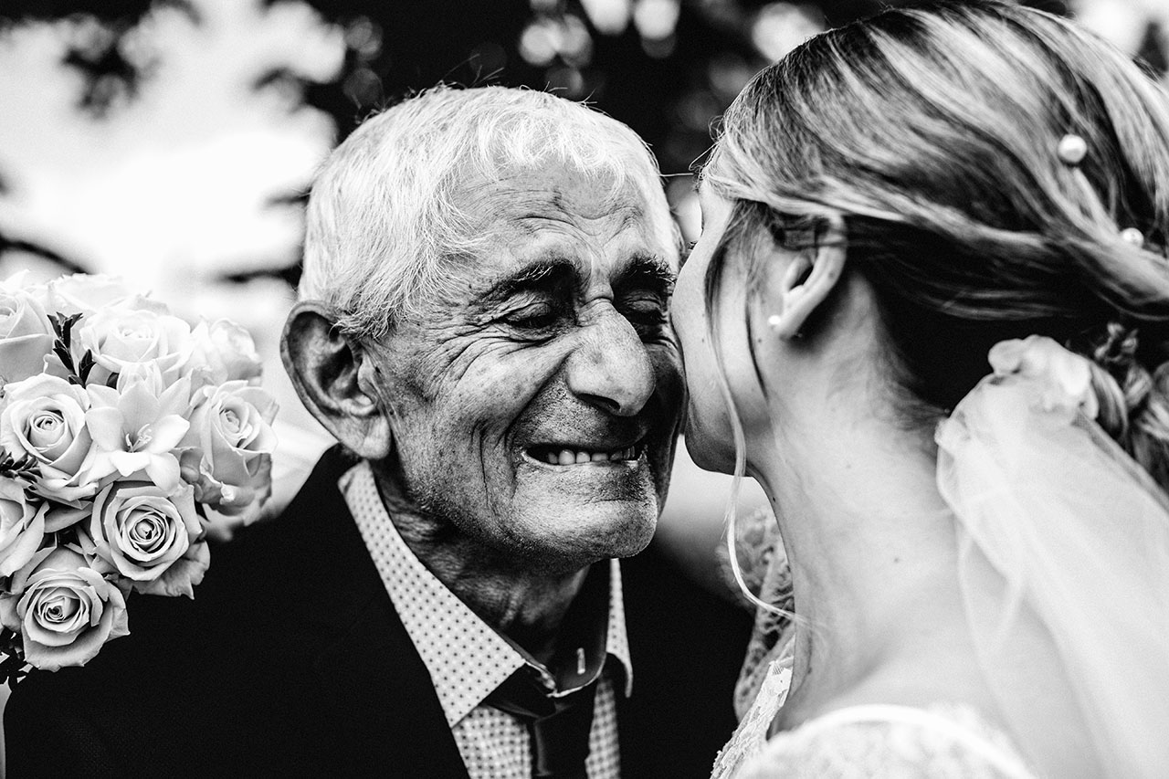 grand dad smiling and crying while hugging the bride