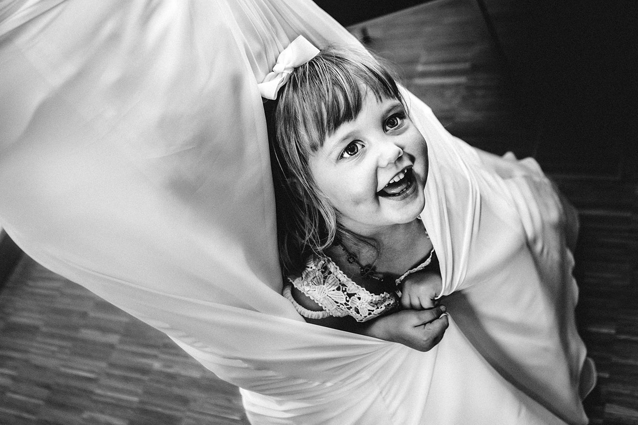 little girl hiding in brides dress