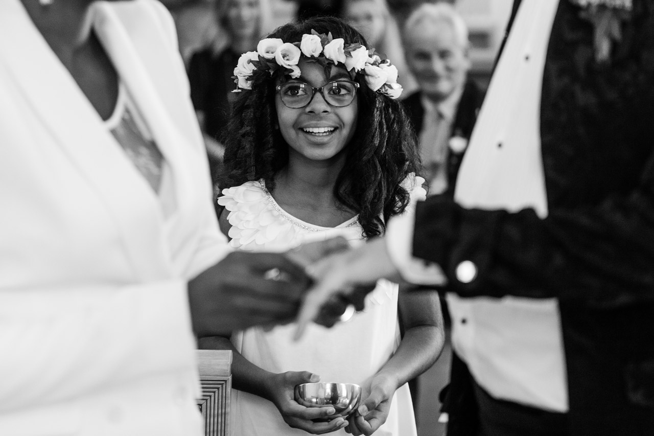 little black girl smiling at her mom while bride and groom exchange rings