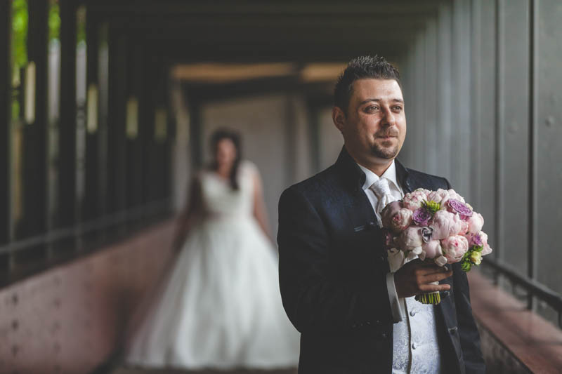 groom holding the bouquet while he waits for his bride