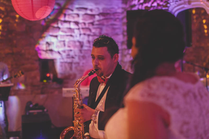 groom playing saxophone tune during wedding party