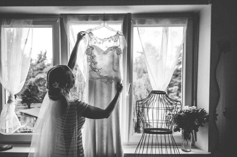 silhouette of the bride hanging her dress at the window