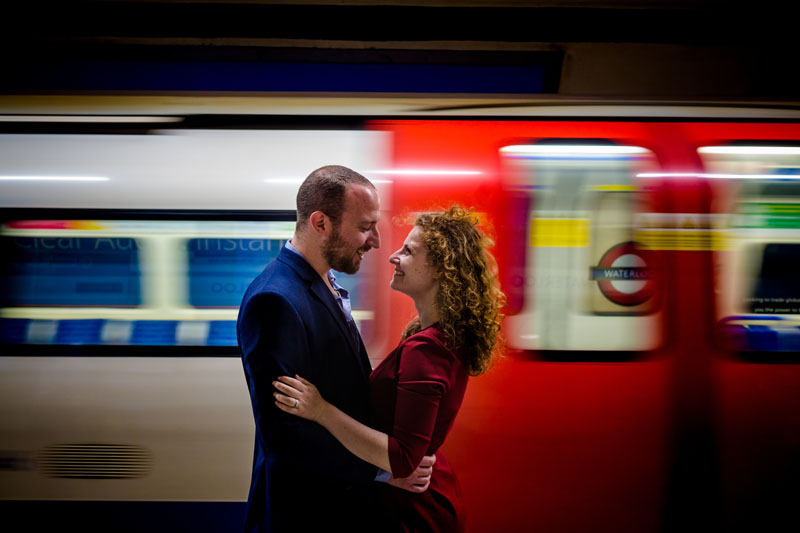 engaged couple posing in front of the train at waterloo tube station in london